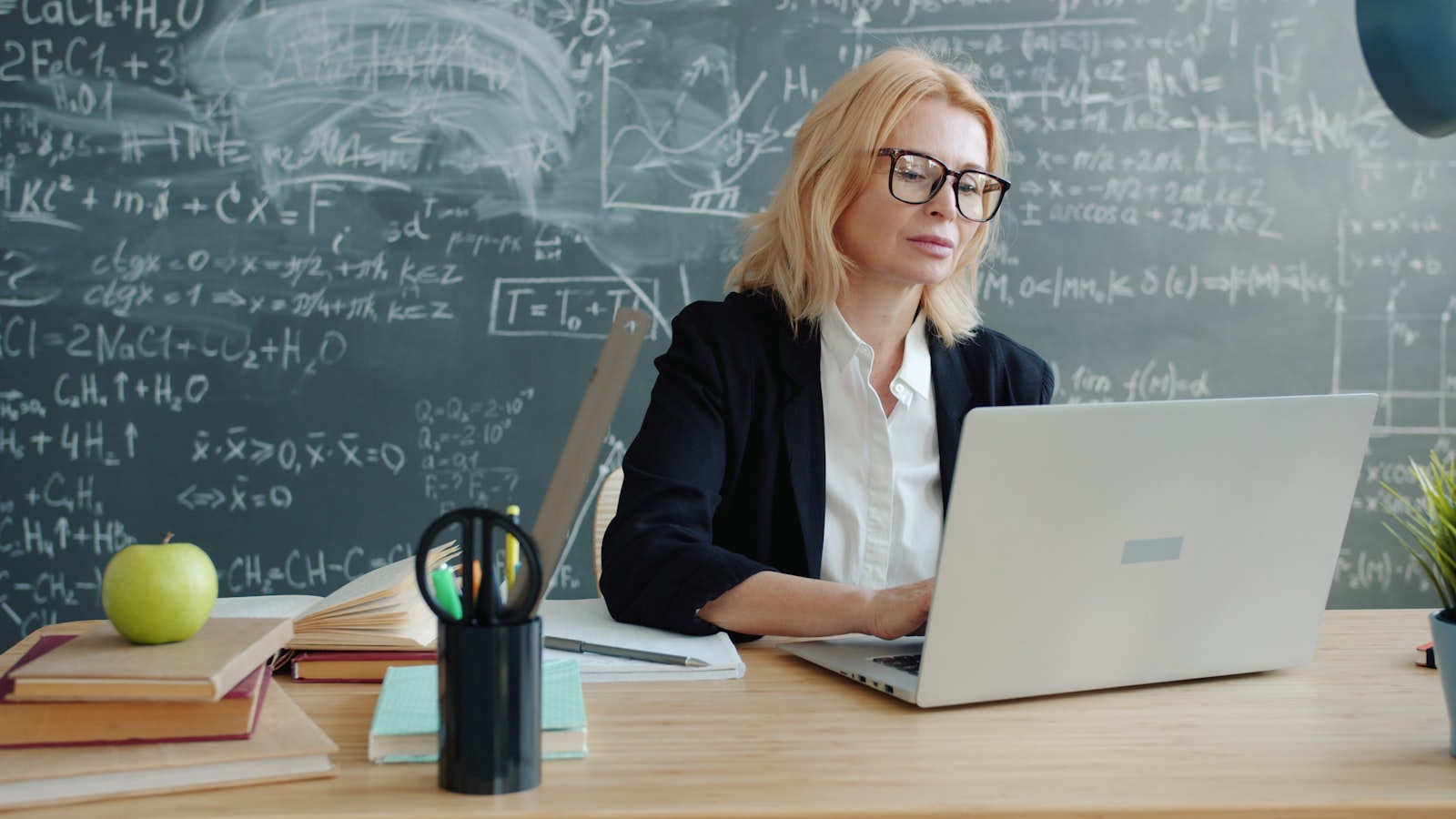 Enseignante utilisant un logiciel de gestion scolaire sur un ordinateur portable en classe